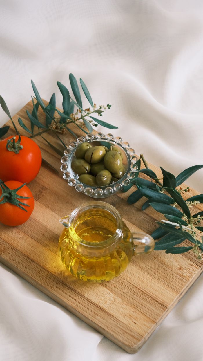 Elegant arrangement of olive oil, tomatoes, and olives on a wooden board.